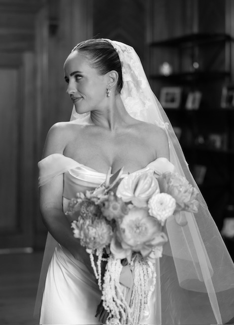 Image shows a beautiful modern, London bride with a Sofia Richie inspired mid height slick bun, veil, wedding dress & bouquet on her wedding day