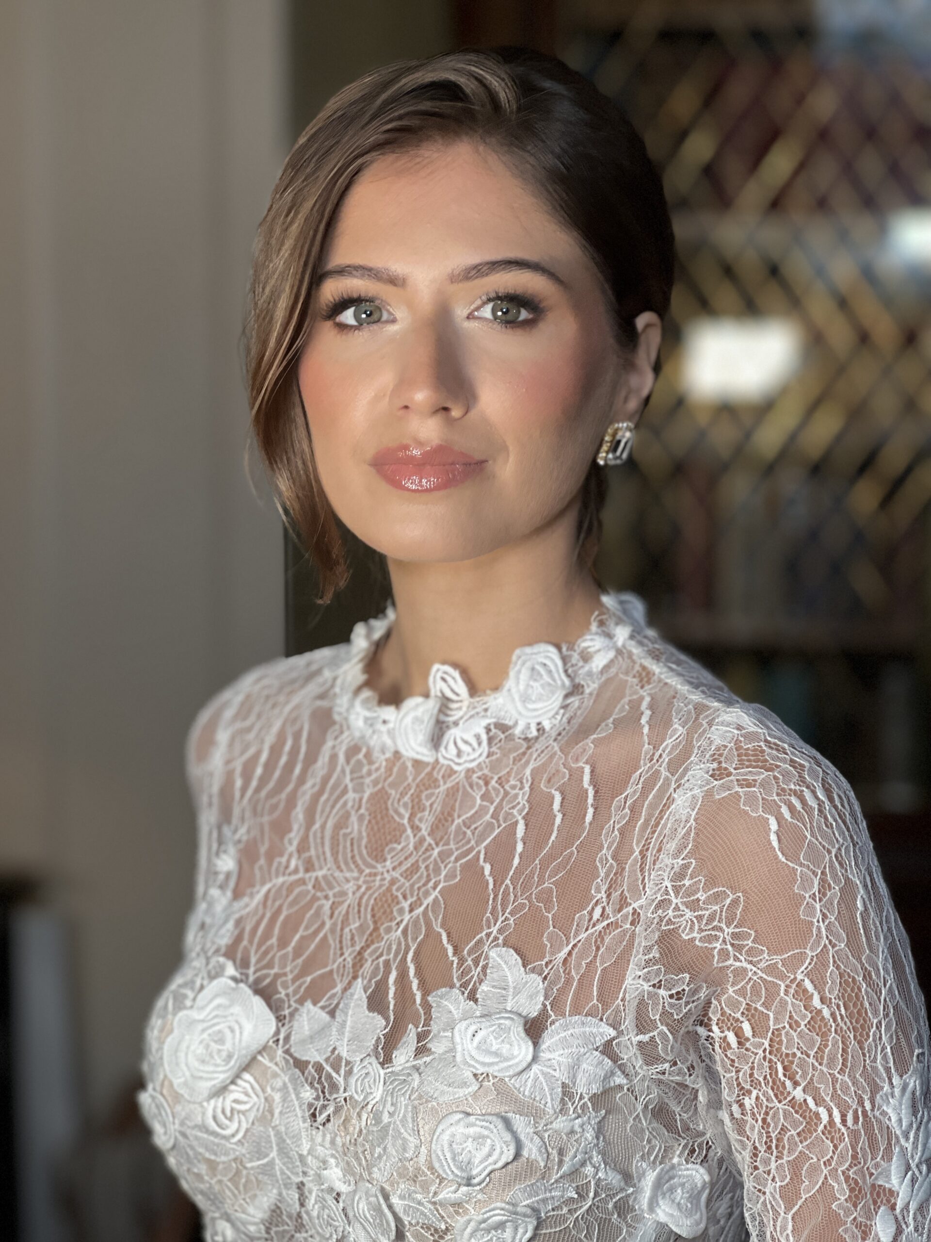 The picture shows a beautiful bride at Somerley House wedding venue in dorset, she has brunette hair which has been pulled into a refined bun by the bridal hairstylist and she has a classic pink toned bridal makeup look created by the makeup artist